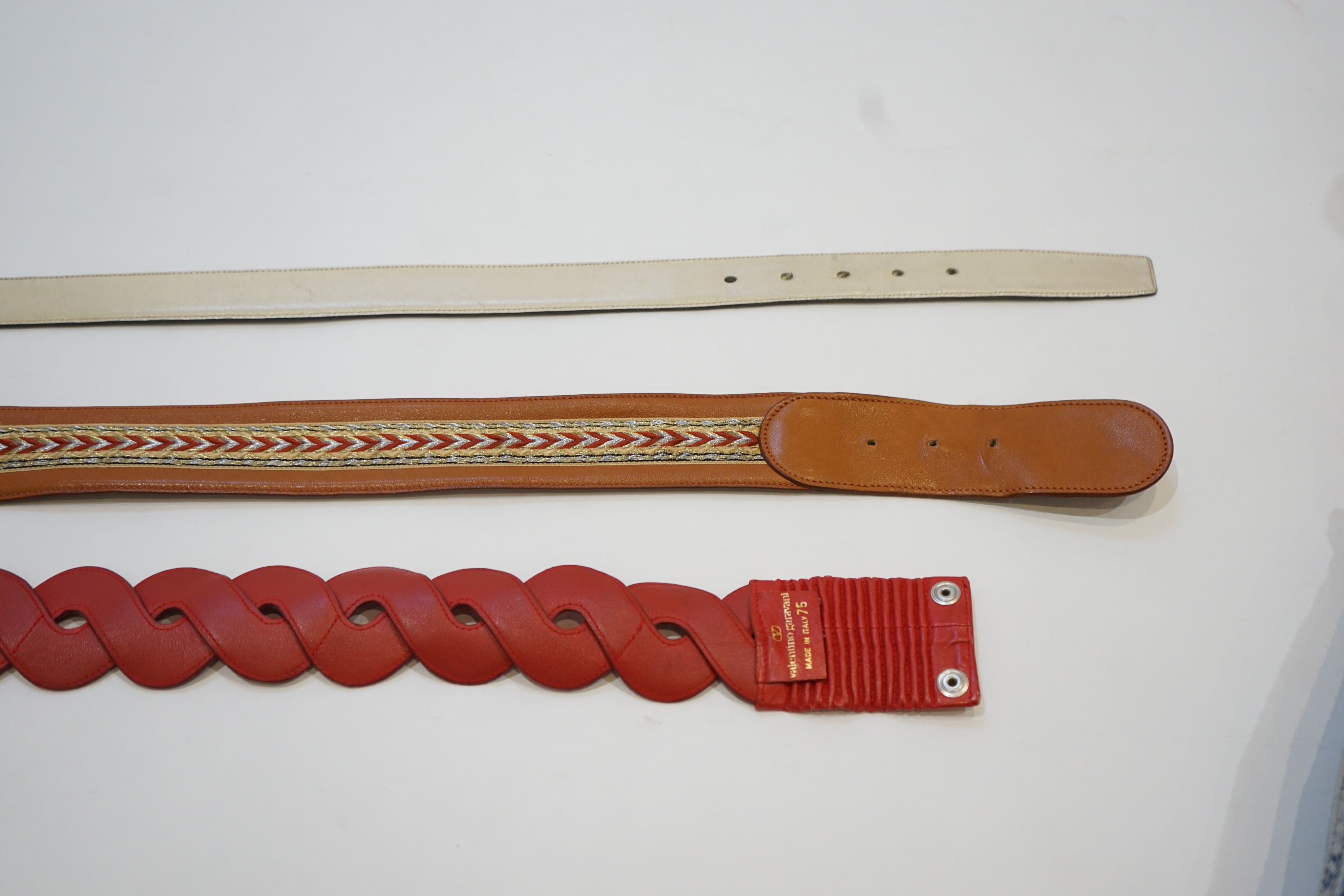 A Gucci cream leather belt and two Valentino belts